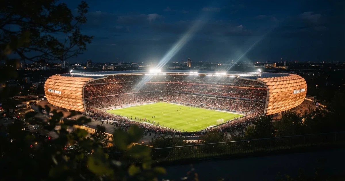 Ein großes Stadion bei Nacht, aus der Ferne unter Flutlicht gesehen, die Ränge hell erleuchtet, der Rasen leuchtend grün.