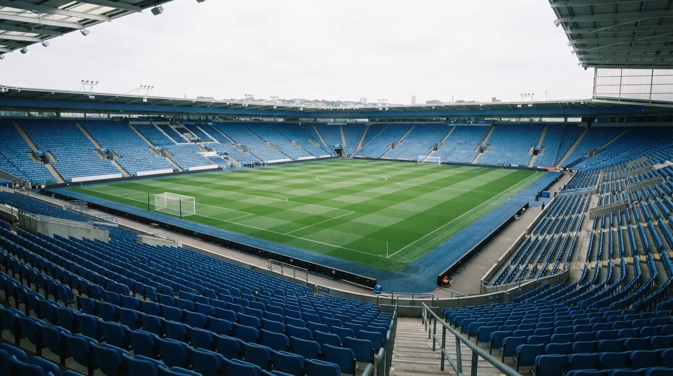 Ein leeres Fußballstadion bei Tageslicht von der Tribüne aus gesehen, der Rasen zeigt gleichmäßige Mähstreifen.