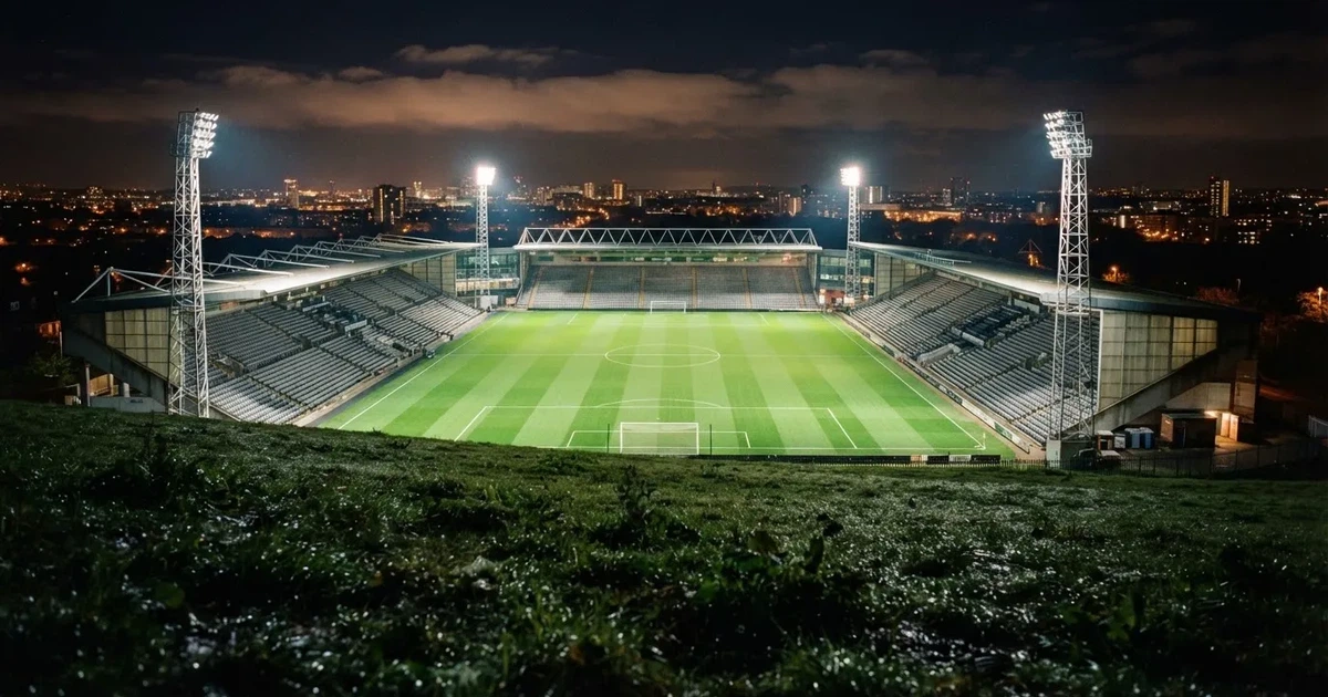 Ein Stadion bei Nacht unter Flutlicht aus der Ferne gesehen, der Rasen ist hell erleuchtet, keine erkennbaren Personen.